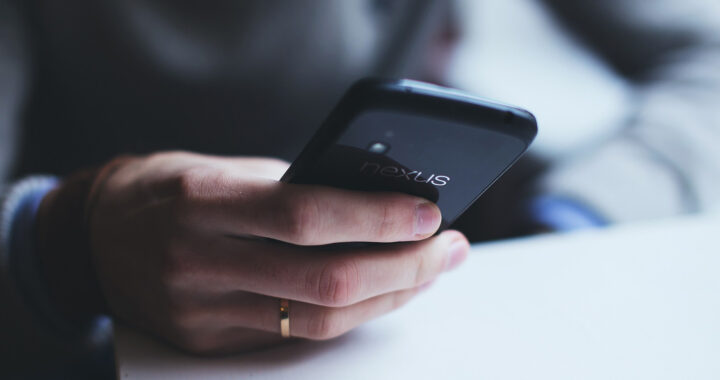 An image of a hand holding a smartphone for the article "Advantages and Disadvantages of Duolingo"