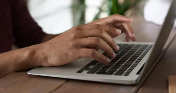 An image of a person who is working on a laptop for the article "Advantages and Disadvantages of Grammarly"