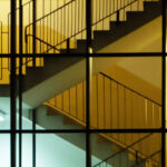 An image of stairs as seen through the window of a building for the article "Top-Down Management: Advantages and Disadvantages"