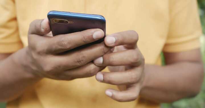 A closeup image of hands of a man holding a smartphone for the article "5G SA vs 5G NSA: What are Standalone and Non-Standalone Modes?"