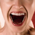 A tight-shot of a woman smiling with her mouth open for the article "Deactivating USAG-1: A Drug For Regrowing Teeth"