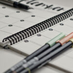 Pens placed on top of a planner for the article "Insights From Science: Why New Year’s Resolutions Fail"