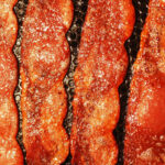 Bacon strips being fried in a pan for the article "Praise the Lard: The United Church of Bacon"