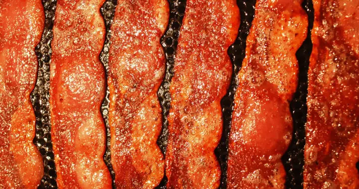 Bacon strips being fried in a pan for the article "Praise the Lard: The United Church of Bacon"