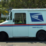 A U.S. Postal Service delivery truck parked in front of a house for the article "United States Postal Service: Importance and Challenges"