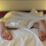 Feet of a man in bed for the article "Labor Force Participation Among U.S. Men Declining"